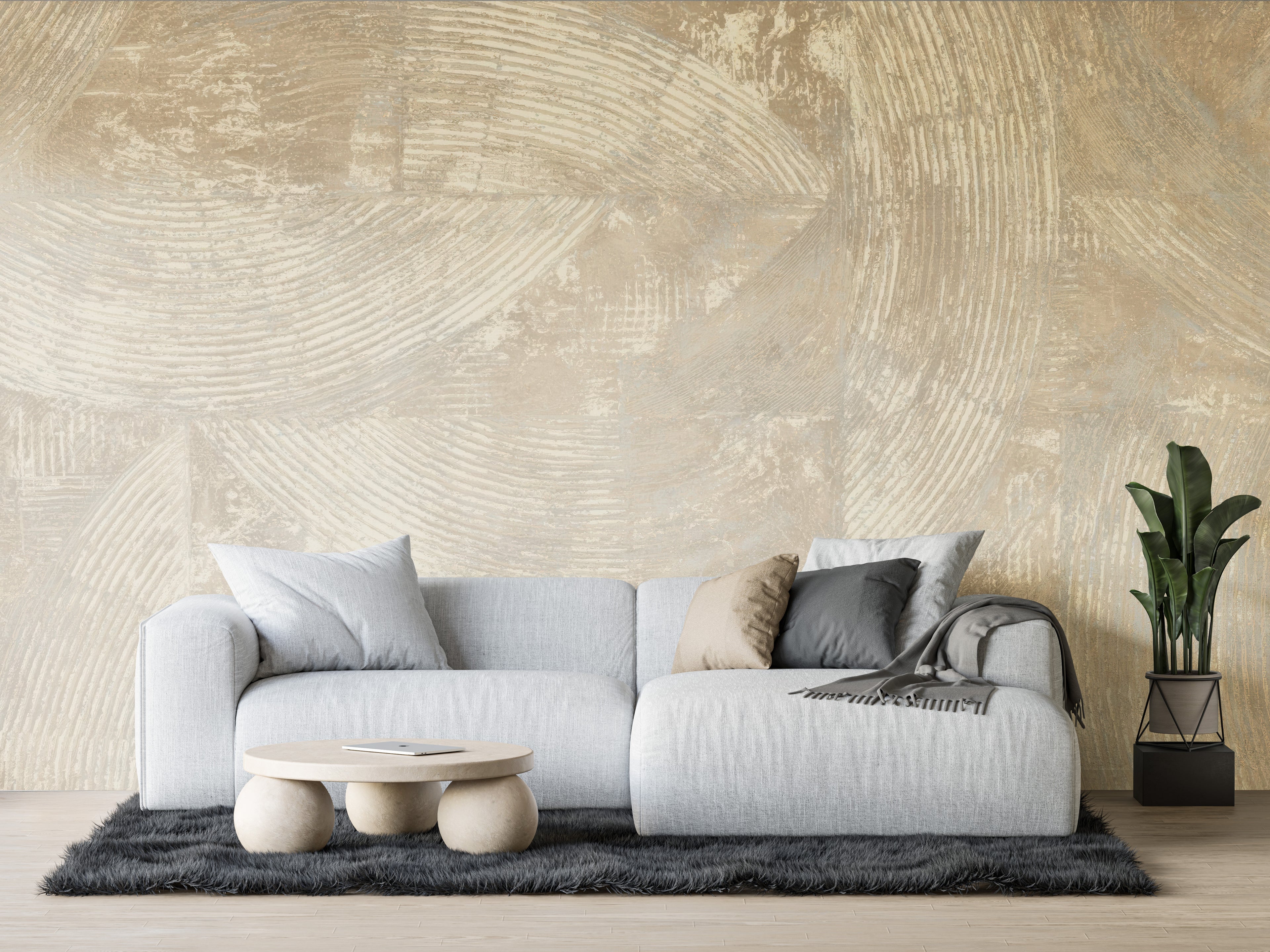Modern living room with a gray sofa, coffee table, and plant against a textured beige wall.